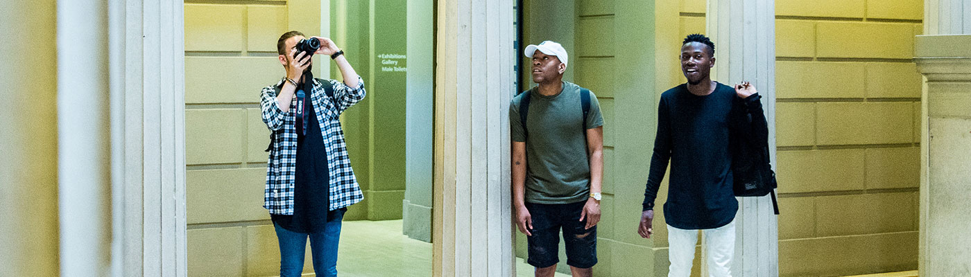 A photograph of three male undergraduates at Manchester Art Gallery