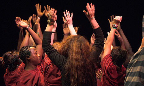 drama students with arms in the air