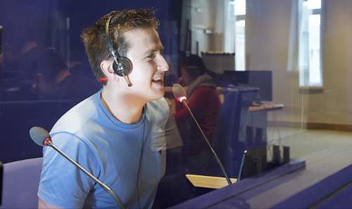 male student wearing headphones talking into microphone in a studio