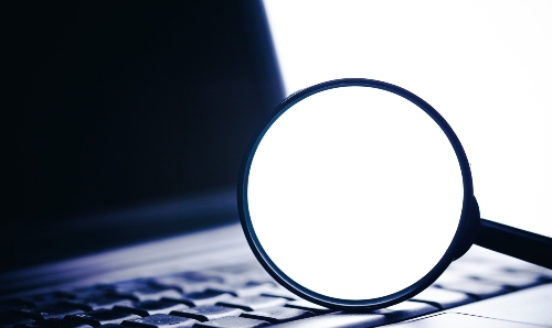 A magnifying glass on a computer keyboard.
